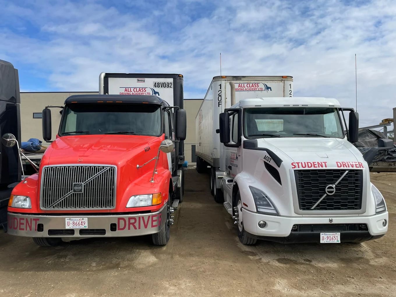 Two All Class Driving Academy student driver trucks parked side by side